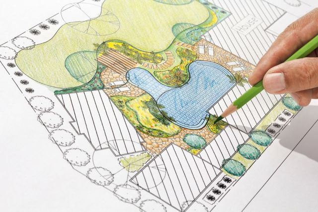 A man puts a pencil onto the drawing of a pool design.
