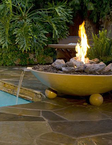 A fire pit with a water feature that drains into a swimming pool.