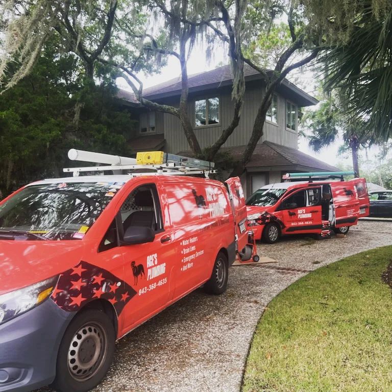 Two Ace's Plumbing vans outside a home.