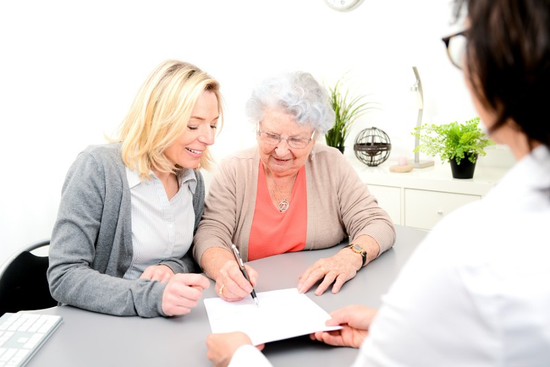 Woman signing some paperwork in front of an attorney.