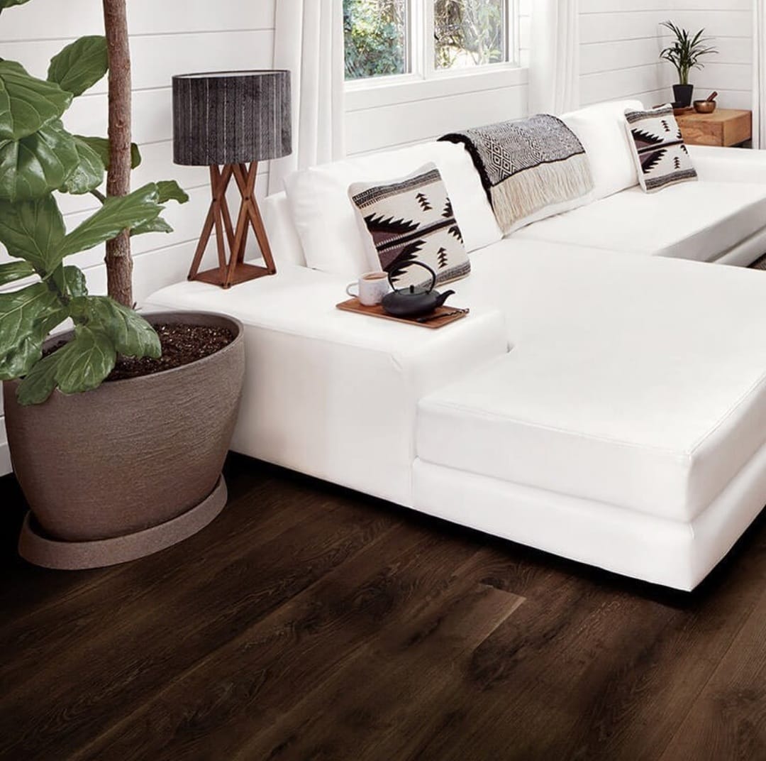 A living room with dark wood flooring and white furniture