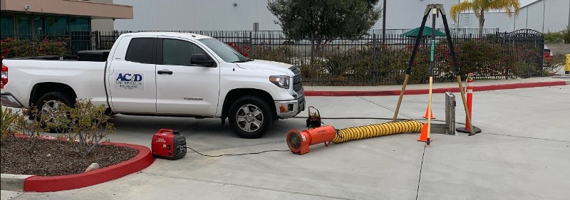 A white pickup truck sets next to equipment inserted into a septic system.