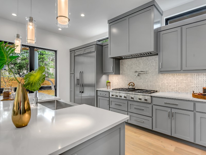 An updated kitchen with stainless steel appliances and gray cabinets.