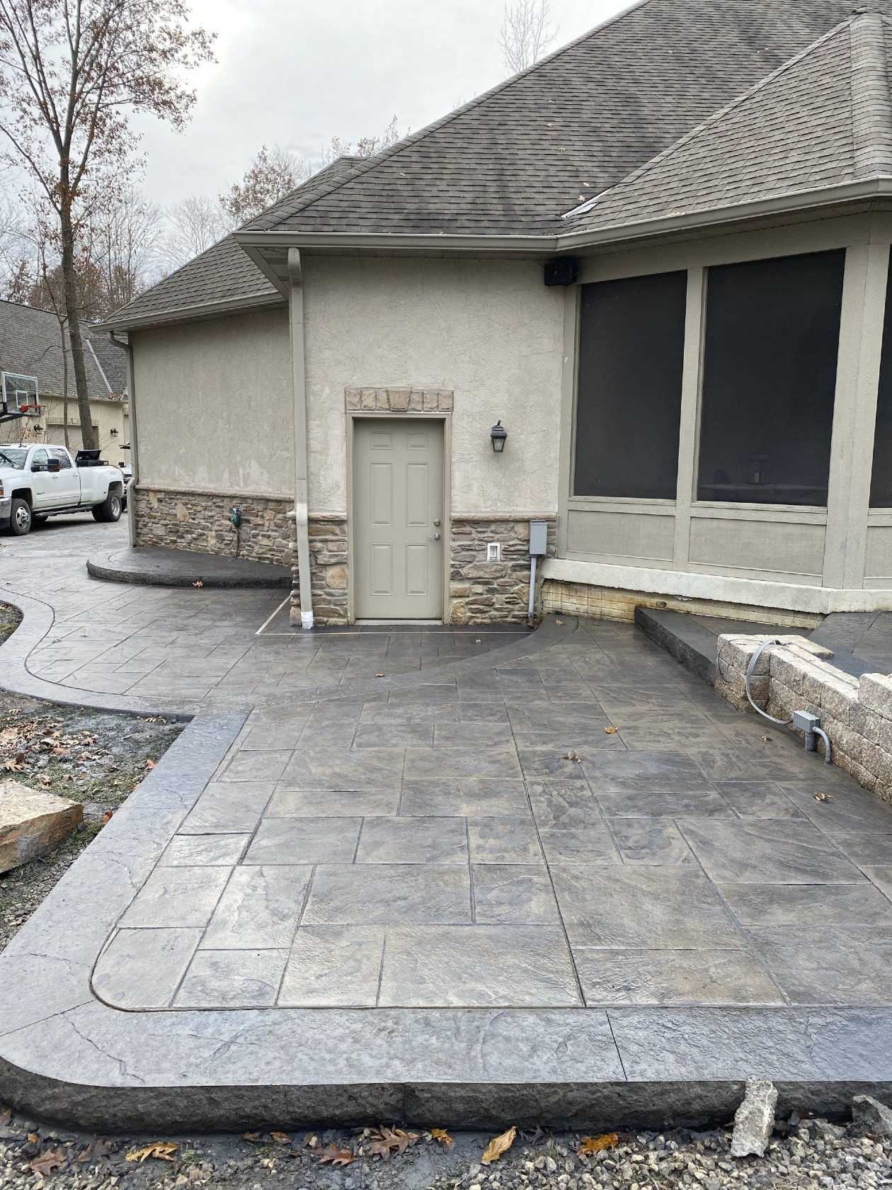 A side patio of a home made of stamped concrete.