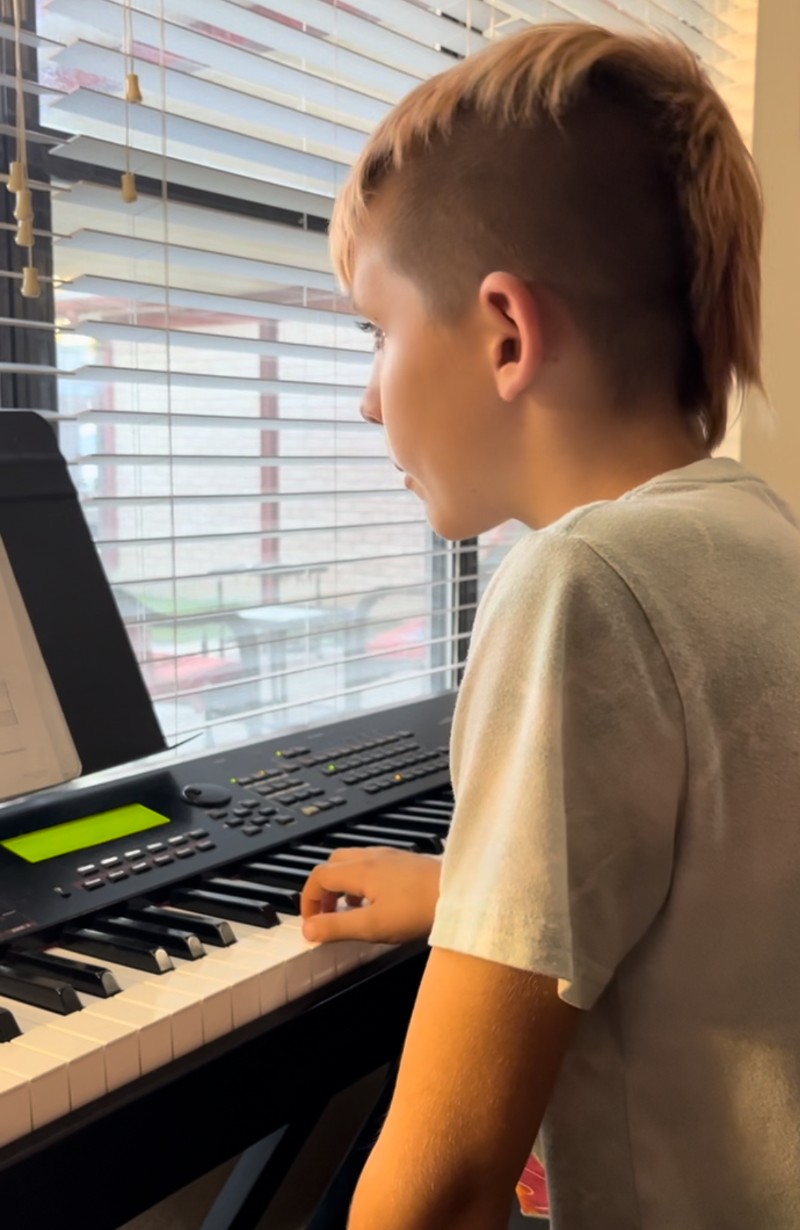 Young boy plays a keyboard.