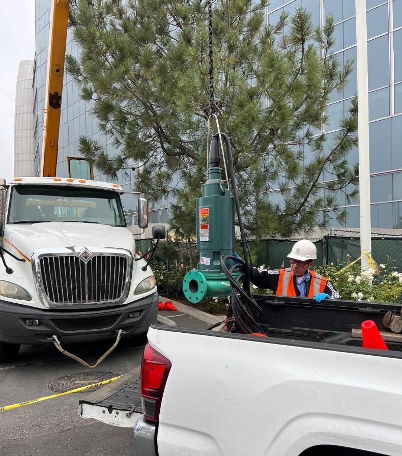 A worker in a hardhat moves pumping equipment into place. 