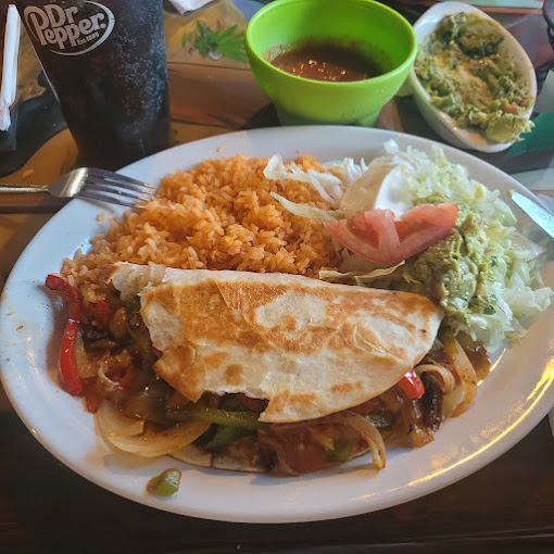 A grilled taco with steak and peppers with guacamole and fried rice on the side.