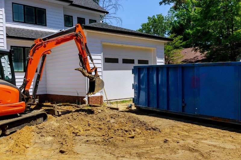 A house with a blue dumpster and an orange crane. 