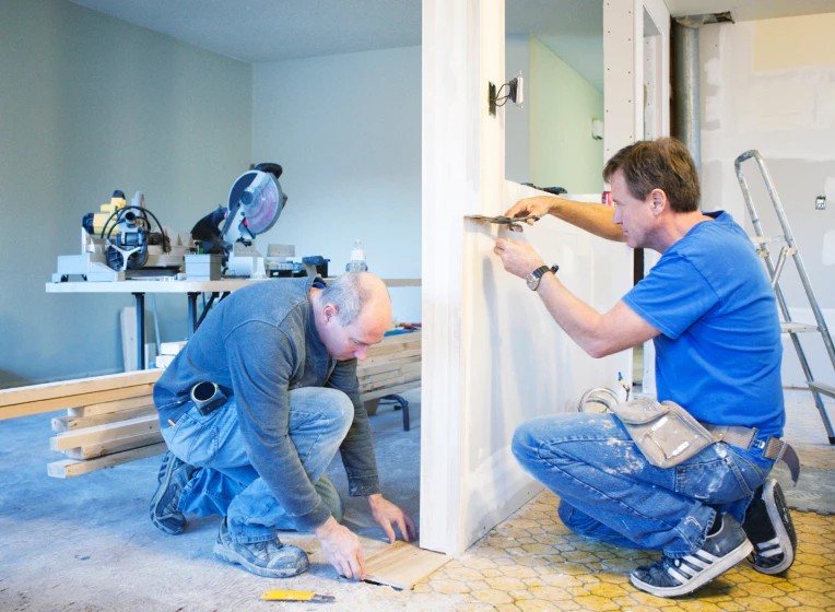 Two construction workers building a kitchen pass-through window.