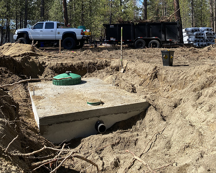 Septic tank in the ground waiting to be covered by a pile nearby of dirt.